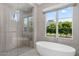 Stylish bathroom with a modern soaking tub and glass-enclosed shower, complemented by a large window at 6235 E Montecito Ave, Scottsdale, AZ 85251