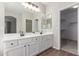 Bathroom featuring double sinks, white cabinets, wood-look floors, and access to the walk-in closet at 12937 W Highland Ave, Litchfield Park, AZ 85340