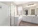 Bathroom featuring white cabinets, double sinks, separate bathtub, and glass-enclosed shower at 12937 W Highland Ave, Litchfield Park, AZ 85340