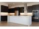 A modern kitchen with dark cabinets, white countertops, and stainless steel appliances at 1436 E Cherrywood Pl, Chandler, AZ 85249
