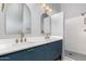 Modern bathroom featuring double sinks with gold fixtures, a large mirror, and a tiled shower at 1859 N Val Vista Dr, Mesa, AZ 85213