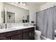 Bathroom featuring dark wood cabinets, a double sink, a large mirror, and gray shower curtain at 3481 N 309Th Ln, Buckeye, AZ 85396