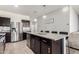 Open-concept kitchen featuring stainless steel appliances, granite countertops, island with seating, and dark wood cabinetry at 3481 N 309Th Ln, Buckeye, AZ 85396