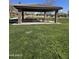 A covered picnic area with stone pillars, a tiled roof, and picnic tables invites gatherings in the lush park at 3481 N 309Th Ln, Buckeye, AZ 85396