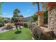 Landscaped backyard with stonework, artificial turf, and lush plants at 4808 N Litchfield E Knl, Litchfield Park, AZ 85340