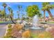 Community entrance featuring a decorative fountain, rock features, and mature palm trees at 4808 N Litchfield E Knl, Litchfield Park, AZ 85340