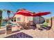 Relaxing outdoor patio with a pool, umbrellas, and dining furniture with stone accent columns at 10851 E Sonrisa Ave, Mesa, AZ 85212