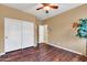 This cozy bedroom features a ceiling fan, spacious closet, and rich wood-look laminate flooring at 10851 E Sonrisa Ave, Mesa, AZ 85212