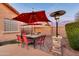 Outdoor dining space featuring a stone gas heater, an umbrella-covered table and views of the landscaped yard at 10851 E Sonrisa Ave, Mesa, AZ 85212