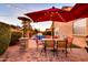 Outdoor patio boasts red umbrellas, stylish furniture, brick flooring, and festive string lights at 10851 E Sonrisa Ave, Mesa, AZ 85212