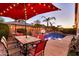 Sparkling pool and patio area, with outdoor dining set, basketball hoop, palm trees, and string lights at 10851 E Sonrisa Ave, Mesa, AZ 85212