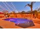 Backyard features a sparkling pool with palm trees and a cozy patio, illuminated by festive string lights at 10851 E Sonrisa Ave, Mesa, AZ 85212
