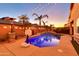 Backyard features a sparkling pool with palm trees and a cozy patio, illuminated by festive string lights at 10851 E Sonrisa Ave, Mesa, AZ 85212