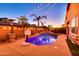 Backyard features a sparkling pool with palm trees and a cozy patio, illuminated by festive string lights at 10851 E Sonrisa Ave, Mesa, AZ 85212