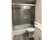 Bathroom featuring gray tiled shower and tub with glass doors and white toilet at 1920 W Lindner W Ave # 108, Mesa, AZ 85202