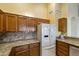 Kitchen boasts granite counters, wood cabinets and a large refrigerator at 23610 S Desert Moon Ct, Sun Lakes, AZ 85248