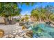 Inviting backyard pool featuring natural rock accents, lush trees, and comfortable patio seating at 10041 N 52Nd Pl, Paradise Valley, AZ 85253