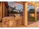 Built-in outdoor grill and kitchen alongside manicured lawn in this private backyard living space at 3241 E Aris Dr, Gilbert, AZ 85298