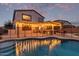 Backyard illuminated at dusk featuring a private pool and covered patio with seating and a built-in grill at 3241 E Aris Dr, Gilbert, AZ 85298