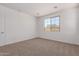 Well-lit carpeted bedroom showcasing a large window, white walls and trim, and a minimalist aesthetic at 12362 W Marguerite Ave, Avondale, AZ 85323