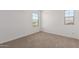 Minimalist carpeted bedroom with two windows that provide ample natural light at 12362 W Marguerite Ave, Avondale, AZ 85323