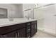 Bathroom featuring double sink vanity with dark cabinets and a glass-enclosed shower at 18366 W Poston Dr, Surprise, AZ 85387
