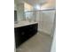 Modern bathroom with dark vanity, frameless shower, and double sinks at 18366 W Poston Dr, Surprise, AZ 85387