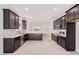 Spacious kitchen boasts dark cabinets, stainless steel appliances, and light countertops and flooring at 18366 W Poston Dr, Surprise, AZ 85387