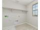 Bright laundry room with white walls, a window, and a built-in shelf for storage at 22831 N 183Rd Dr, Surprise, AZ 85387