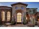 Stunning stone exterior of a luxury home with arched entryway and desert landscaping at 27256 N 97Th Pl, Scottsdale, AZ 85262