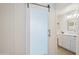 Translucent glass barn door leads into a bathroom with a white vanity, toilet, and modern fixtures at 20100 N 78Th Pl # 1040, Scottsdale, AZ 85255