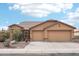 Beige house with two-car garage, landscaping, and a paved driveway at 3376 S 256Th Dr, Buckeye, AZ 85326