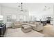 Spacious living room with L-shaped sofa, large TV, and adjacent kitchen at 3376 S 256Th Dr, Buckeye, AZ 85326