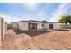 Exterior view of a backyard with dirt and a patio along the rear of the bright white house at 5528 W Sunnyslope Ln, Glendale, AZ 85302