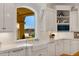 White kitchen with farmhouse sink, custom cabinetry, and a view of the backyard at 1233 E Salado Cir, Mesa, AZ 85203