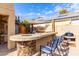 Outdoor kitchen with built-in grill, mini-fridge, and bar seating at 2315 S 173Rd Dr, Goodyear, AZ 85338