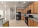Well-lit kitchen features black appliances, tile floors, granite counters and light wood cabinets at 42374 W Avella Dr, Maricopa, AZ 85138