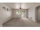 Spacious living room with a ceiling fan, neutral carpet, and sliding glass door to backyard at 42374 W Avella Dr, Maricopa, AZ 85138