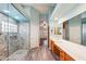 Elegant bathroom with a walk-in shower, double vanity, and stone tile at 7869 W Kristal Way, Glendale, AZ 85308