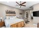 Comfortable bedroom with a ceiling fan, flatscreen TV, rustic bed frame, and an ensuite bathroom at 1457 E Copper Holw, Queen Creek, AZ 85140