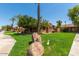 A well-maintained front yard with mature trees, rocks, and lawn at 4511 W Valencia Dr, Laveen, AZ 85339