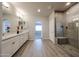Well-lit bathroom featuring a large vanity with double sinks, a sleek glass-enclosed shower, and modern tile flooring at 14200 W Village Pkwy # 113, Litchfield Park, AZ 85340