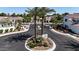 Street-level aerial view of gated community entrance with palm trees and landscaping at 14200 W Village Pkwy # 113, Litchfield Park, AZ 85340
