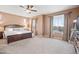 King-size bed, ceiling fan, and large windows with natural light at 17673 W Agave Rd, Goodyear, AZ 85338