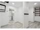 Hallway with stylish wood-look tile flooring and convenient coat hooks, leading to a bathroom with a white vanity at 2161 E Flintlock Way, Chandler, AZ 85286