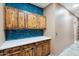 Well-organized laundry room with blue tile and wooden cabinets with white countertop for added functionality at 2161 E Flintlock Way, Chandler, AZ 85286