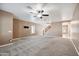 Spacious carpeted living room featuring a ceiling fan and staircase at 2161 E Flintlock Way, Chandler, AZ 85286