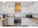 Modern kitchen with white cabinets, wood range hood, and stainless steel appliances at 9412 S 35Th Gln, Laveen, AZ 85339