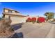 Two-story house with beige walls and a two-car garage; red flowering bushes at 10760 W Monte Vista Rd, Avondale, AZ 85392