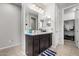 Bathroom with dark vanity, large mirror, and walk-in closet at 18254 W Via Montoya Dr, Surprise, AZ 85387